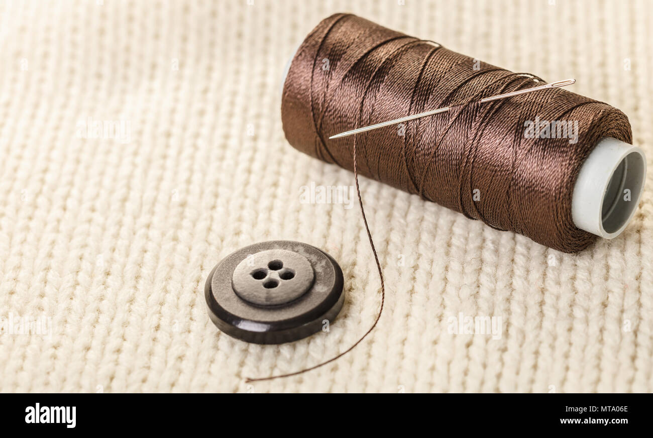 colored thread and buttons on white knitted fabric Stock Photo - Alamy