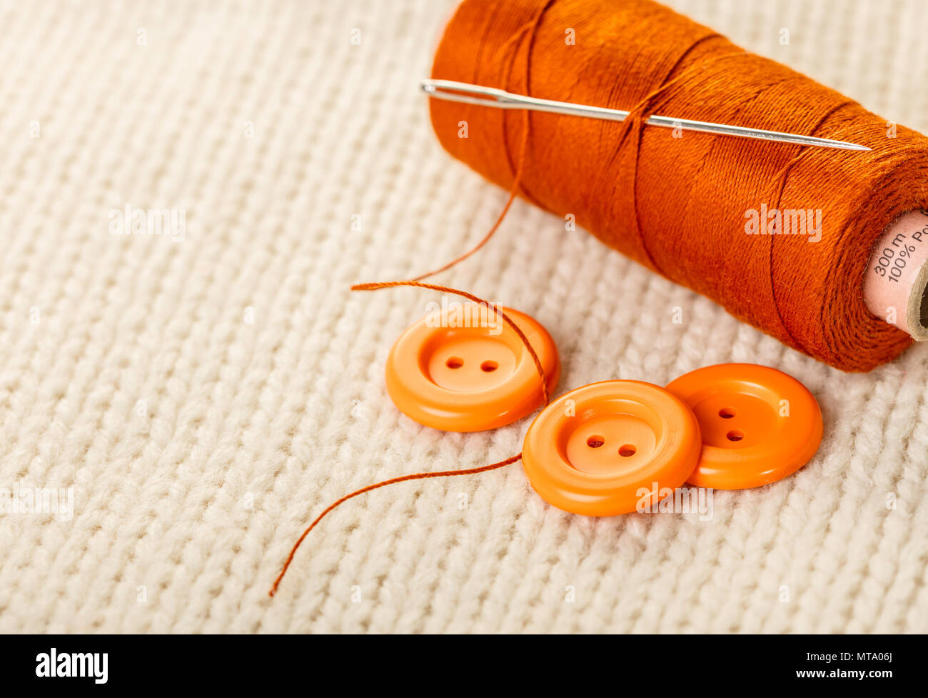 colored thread and buttons on white knitted fabric Stock Photo - Alamy