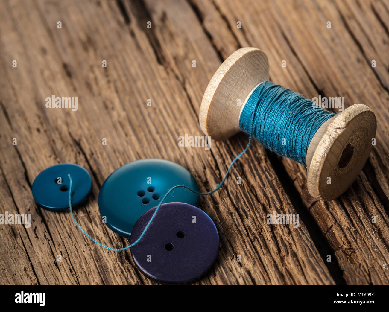 spool of threads and buttons on a wooden background Stock Photo - Alamy
