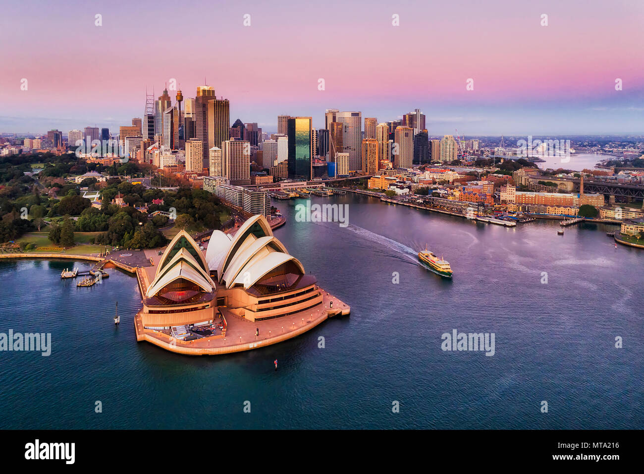 Pinkish colourful sunrise over Sydney city CBD on waterfront of Harbour around Circular quay with major architectural landmarks and symbols of Austral Stock Photo