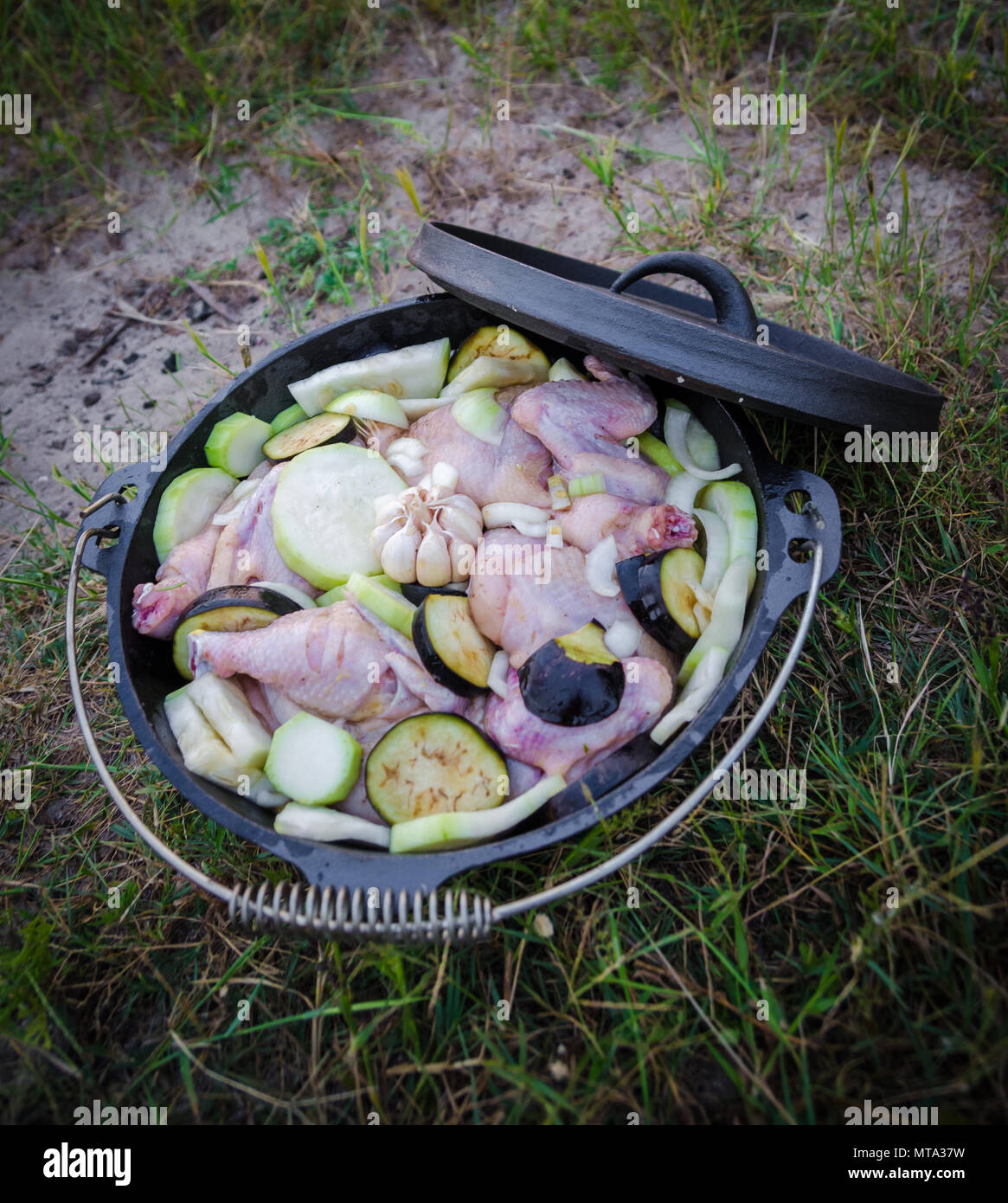 Fresh chicken, aubergine and sqaush stew in cast iron pot or dutch oven to be cooked on campfire Stock Photo