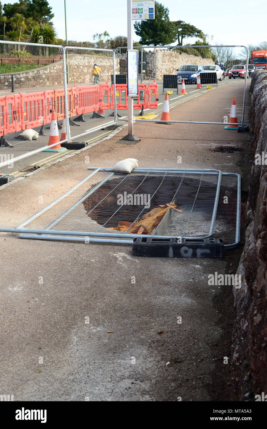 Safety fencing covering a sink-hole in the pavement during repairs. Stock Photo
