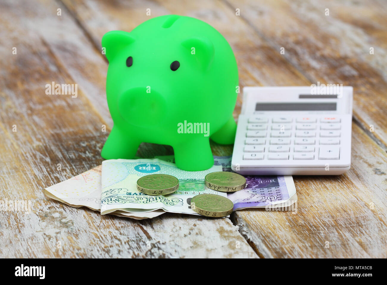 British banknotes and coins, piggy bank and calculator on rustic wooden surface Stock Photo