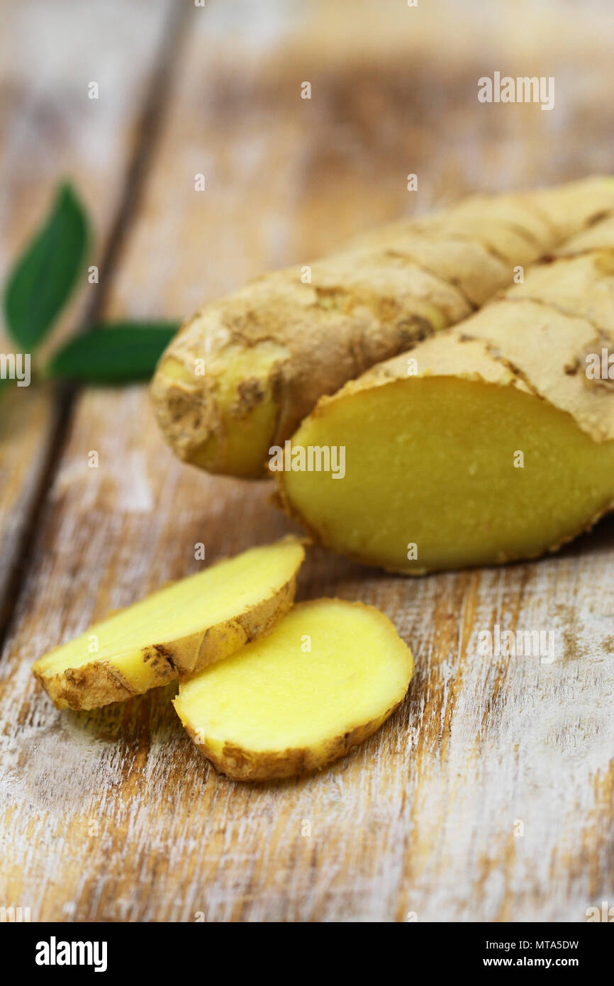 Slices of fresh ginger on rustic wooden surface with copy space Stock Photo