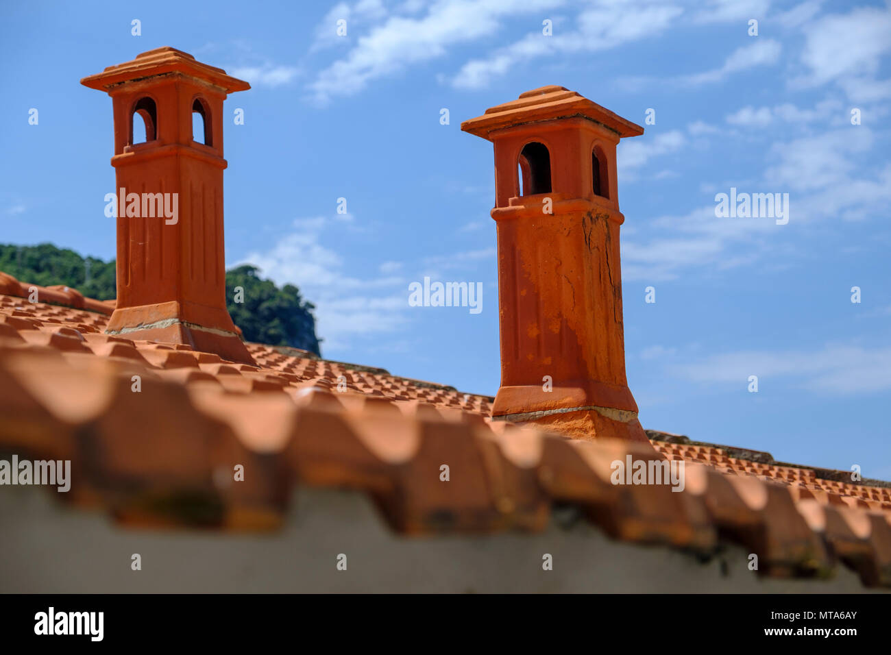 Beautiful red terracotta chimneys on a tiled rooftop in Portovenere Italy against blue sky Stock Photo