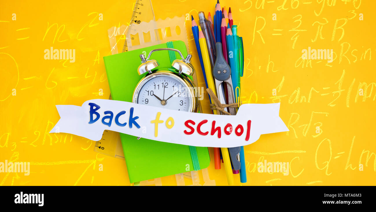 back to school concept - alarm clock and school supplies with back to ...