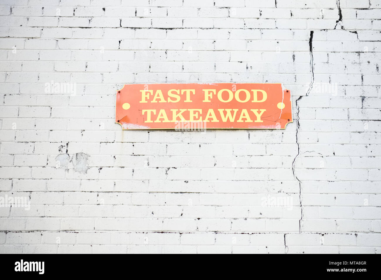 fast food takeaway sign on wall white brick background orange signage fast food takeaway sign on wall white brick background orange signage Stock Photo