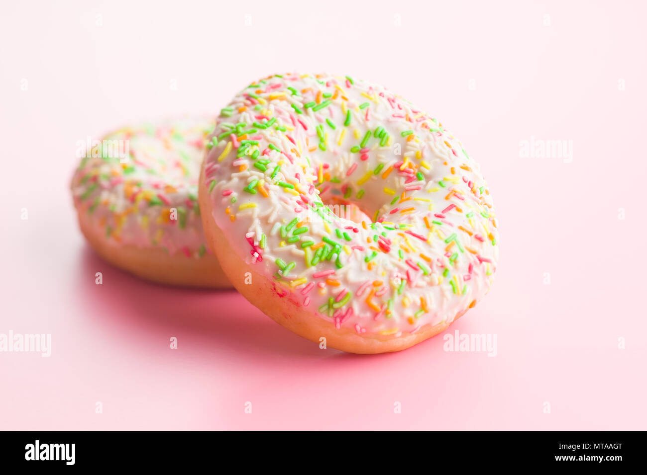 Sweet sprinkled donuts on pink background. Stock Photo