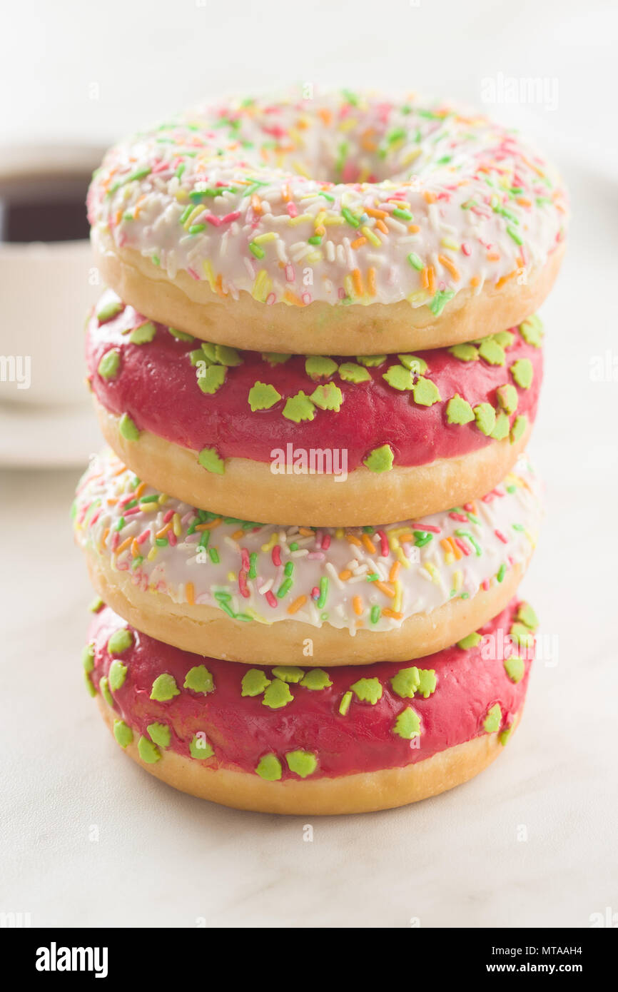 Sweet sprinkled donuts on white kitchen table. Stock Photo