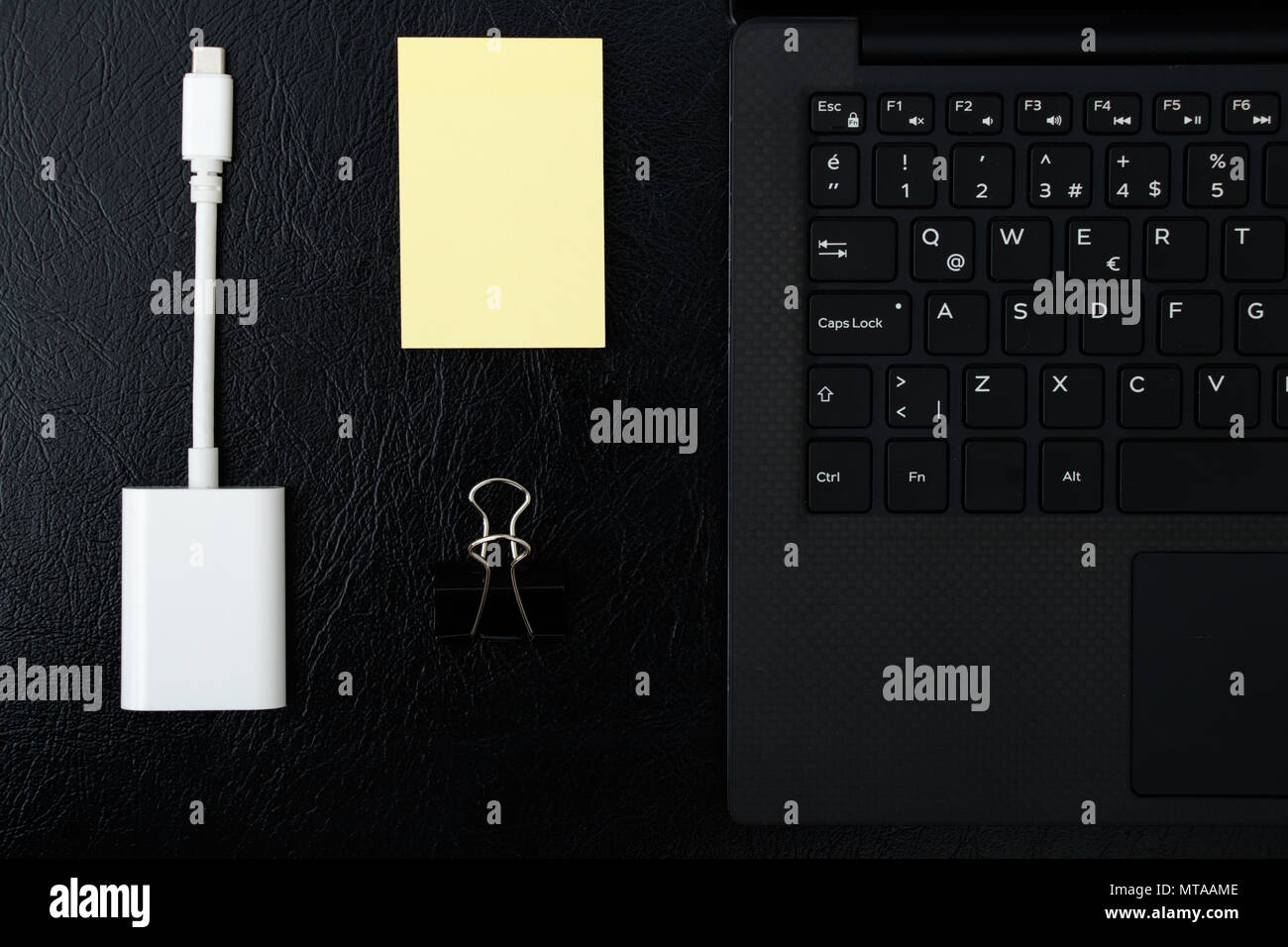 Overhead of office table with laptop, computer keyboard and sticky