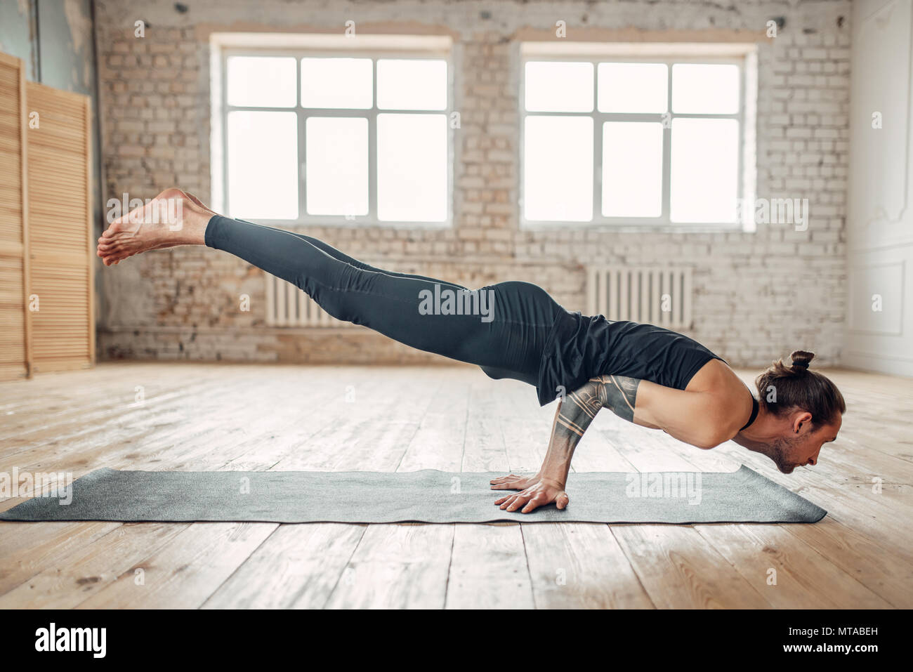 Male yoga standing on hands upside down. Exercise on mat in gym with