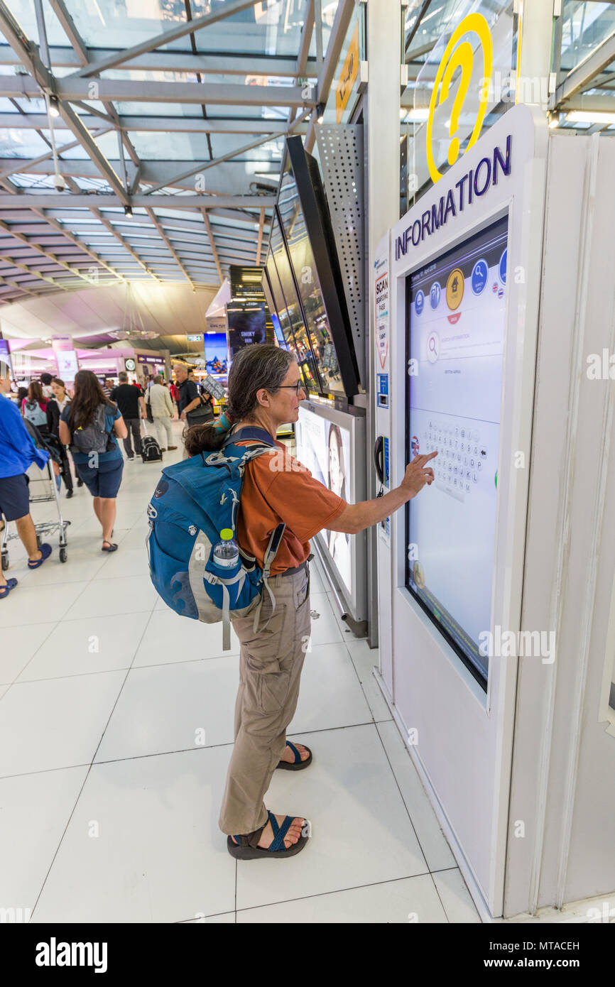 Woman using interactive information board, concourse at airport, Bangkok, Thailand Stock Photo