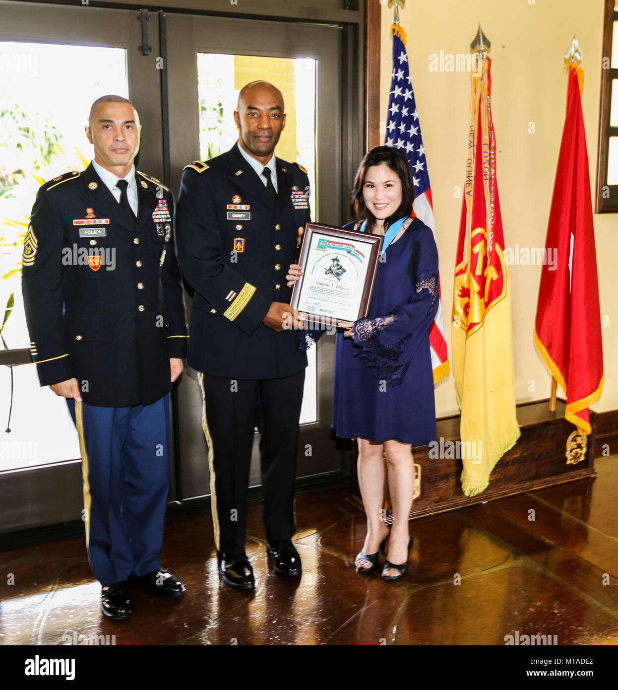 The command team for the 94th Army Air and Missile Defense Command, Brig. Gen. Sean A. Gainey (middle) and Command Sgt. Maj. John W. Foley (left), present the Lt. Col. Thomas Knowlton Award to Ms. Valerie T. Makino, lead Korea branch analyst, Northeast Asia division, PACOM Joint Intelligence Operations Center during the 94th AAMDC Knowlton Awards Ceremony held at the Ka Makani Community Center, Joint Base Pearl Harbor-Hickam, Hawaii April 19. The Knowlton Award was established in June 1995 and recognizes individuals for making significant contributions during their careers to the Military Inte Stock Photo