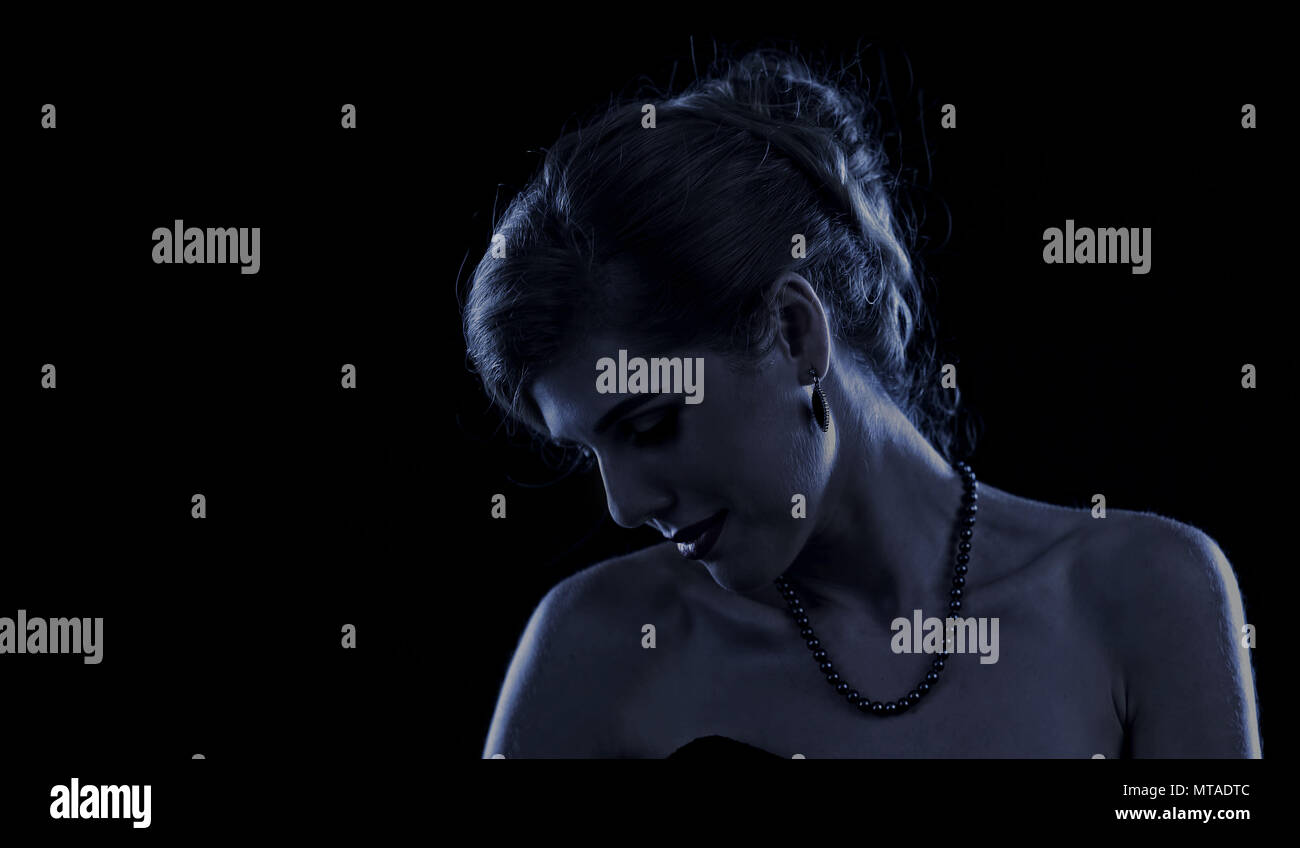 Woman in little black cocktail dress with bare shoulders on black