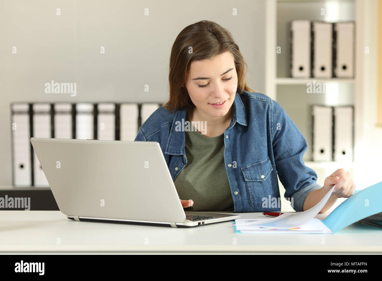 Casual intern working comparing documents online on a desktop at office Stock Photo