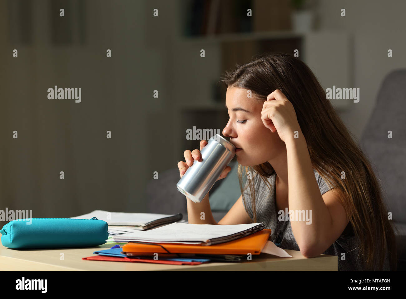 Studious teen studying drinking energy beverage while is studying in