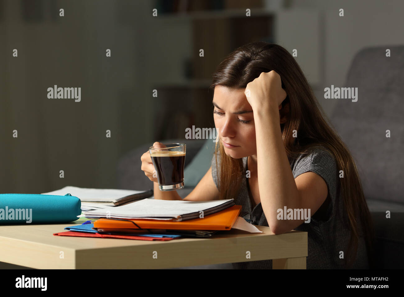 Tired student studying hard late hours drinking coffee at home Stock Photo