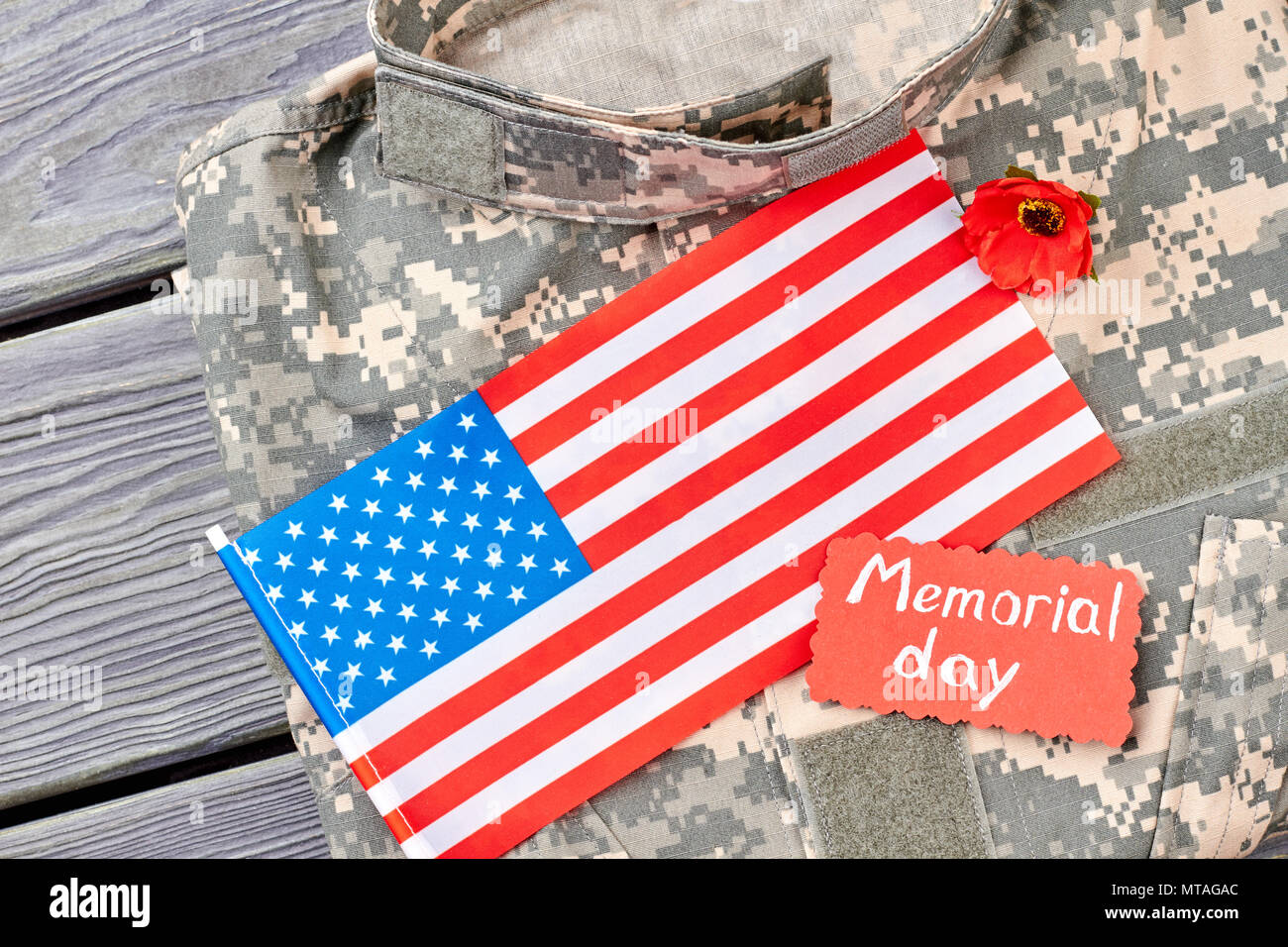 Military camouflage clothes and us flag. Close up. Grey wooden desk background. Stock Photo