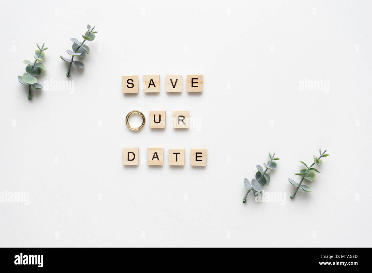 Wooden letters spelling save our date, oregano branches and wedding