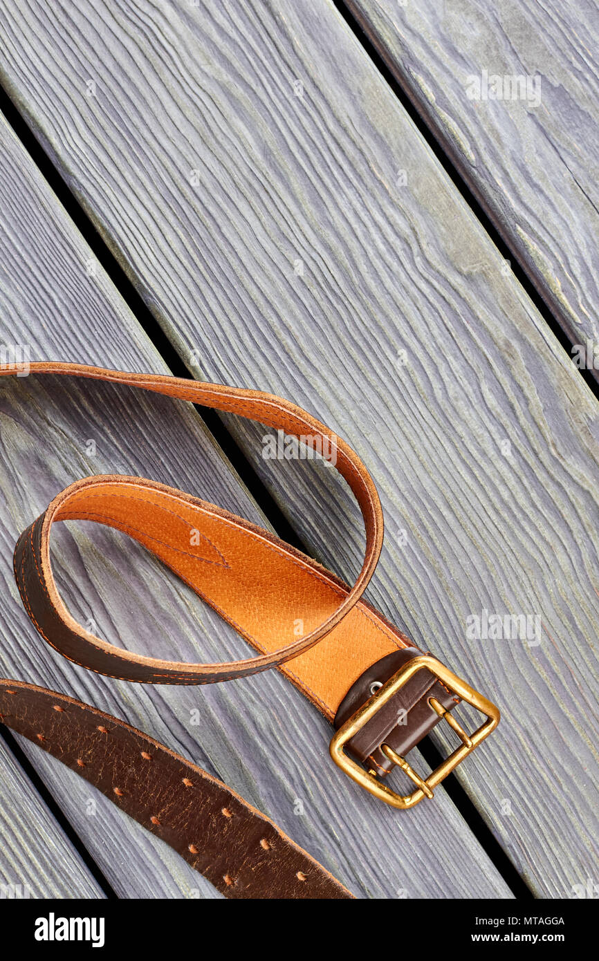 Golden belt buckle. Grey wooden desk background. Stock Photo