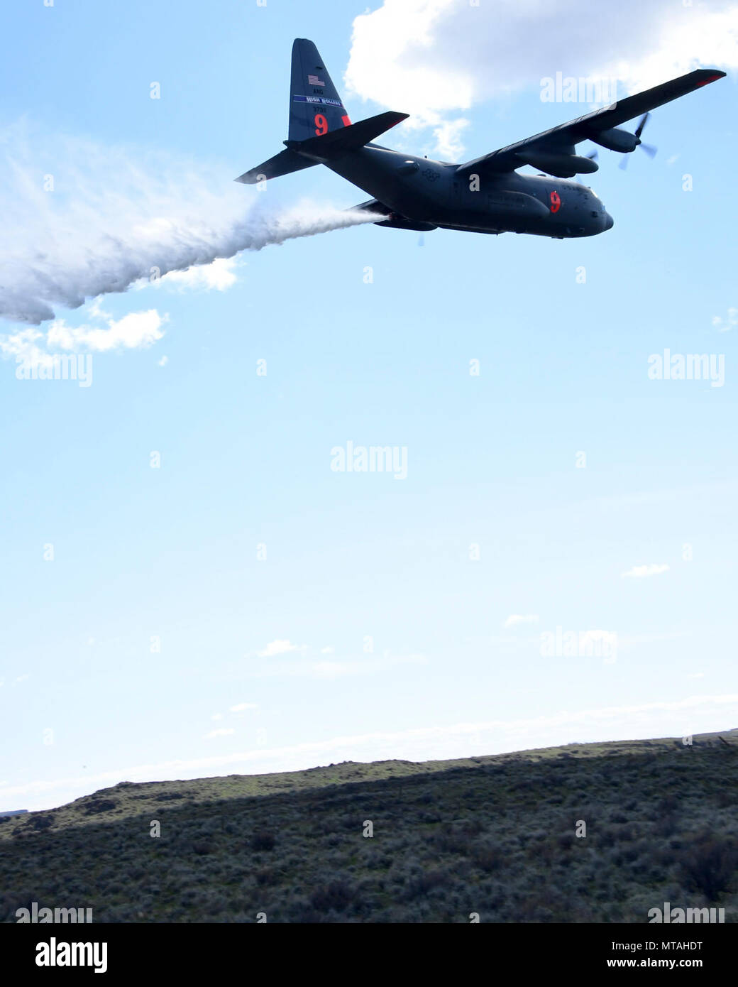 A C130h aircraft loaded with the MAFFS (Modular Airborne Fire Fighting System) from the 152rd Airlift Wing of Reno, Nevada drops a water line while training to contain wildfires just outside Boise, Idaho. April 21, 2017. More than 400 personnel of four C-130 Guard and Reserve units — from California, Colorado, Nevada and Wyoming, making up the Air Expeditionary Group — are in Boise, Idaho for the week-long wildfire training and certification sponsored by the U.S. Stock Photo