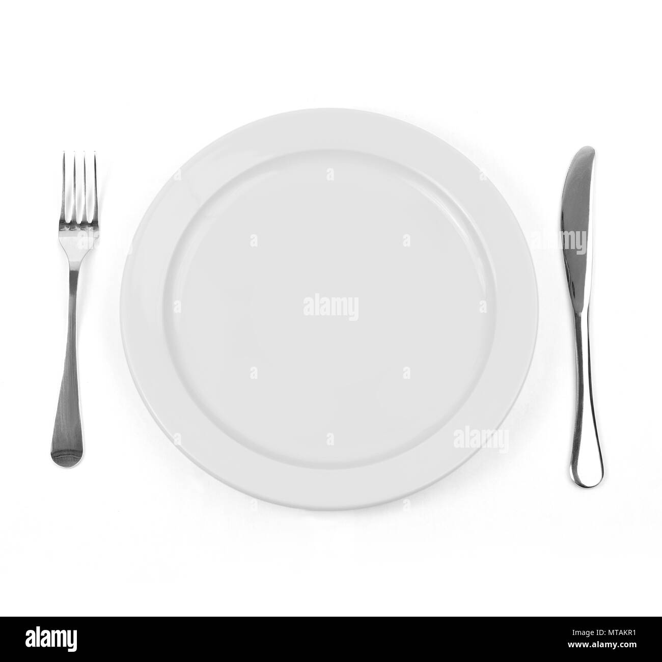 Empty dinner plate with knife and fork on white Stock Photo