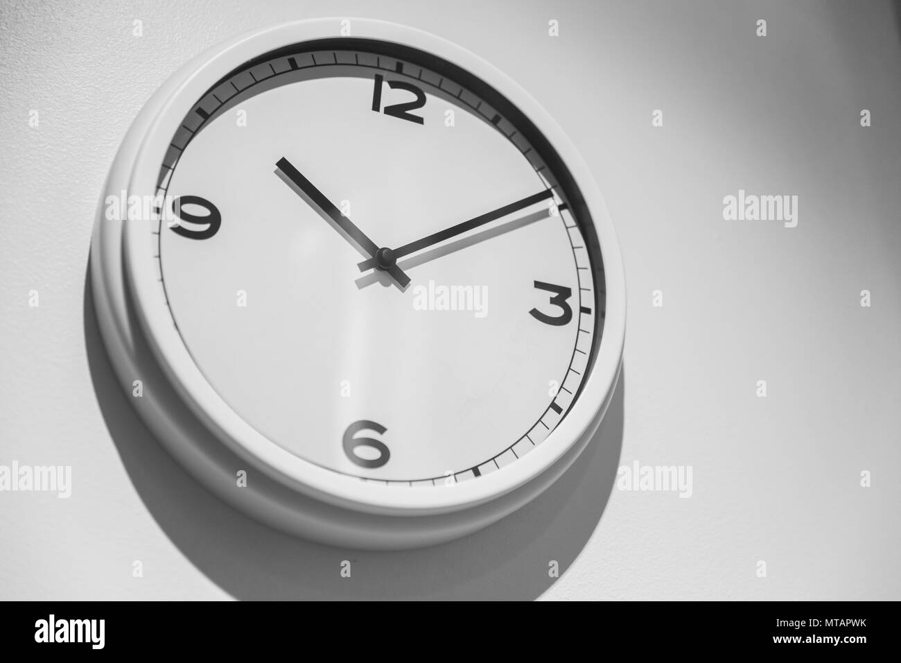 Minimalist Clock or Simple white clock hang on white wall with space for text. Stock Photo