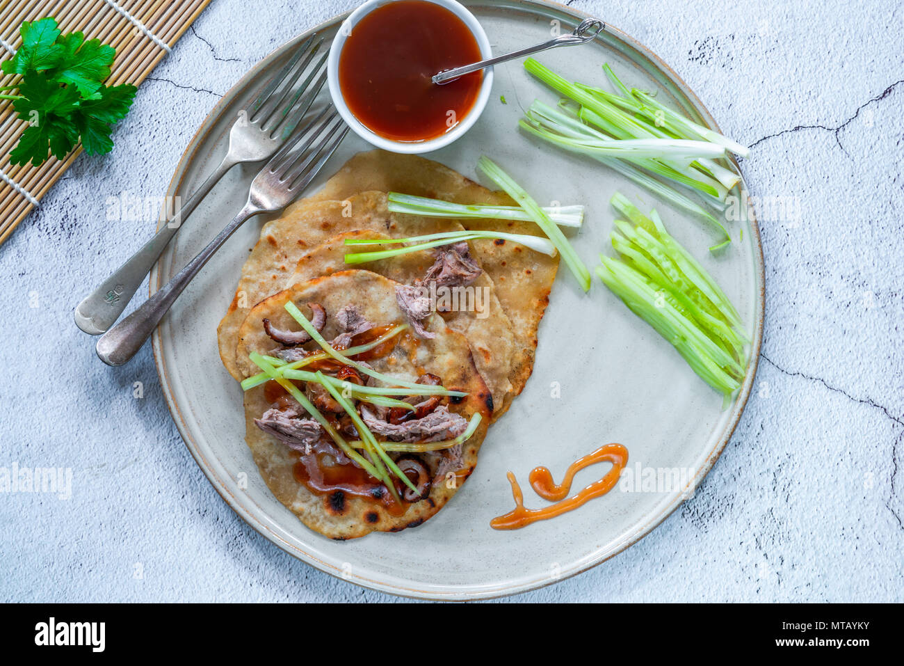 Crispy duck with pancakes, plum sauce, shredded cucumber and spring onion Stock Photo