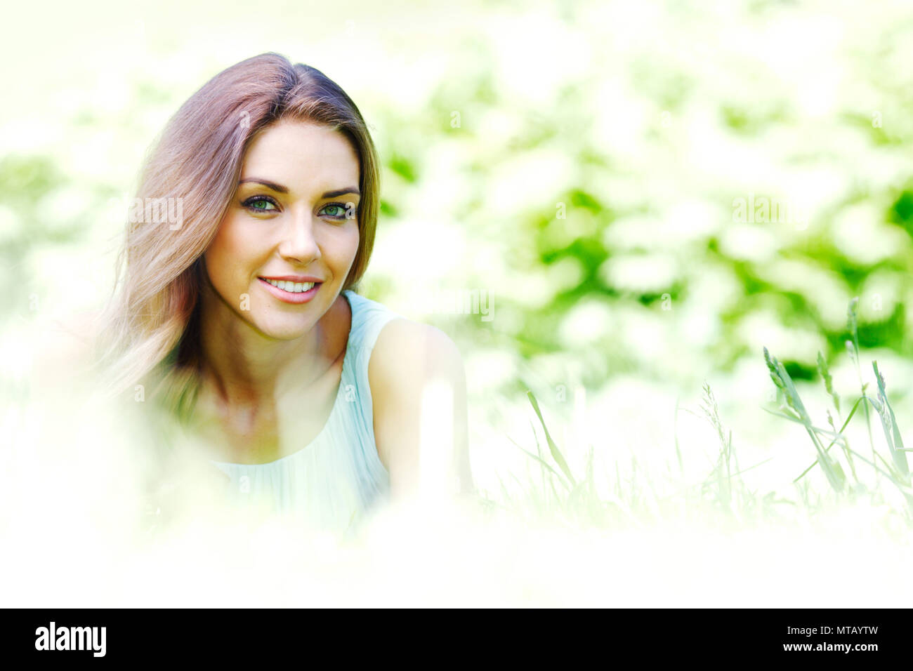 beautiful young woman in blue dress lying on grass Stock Photo - Alamy