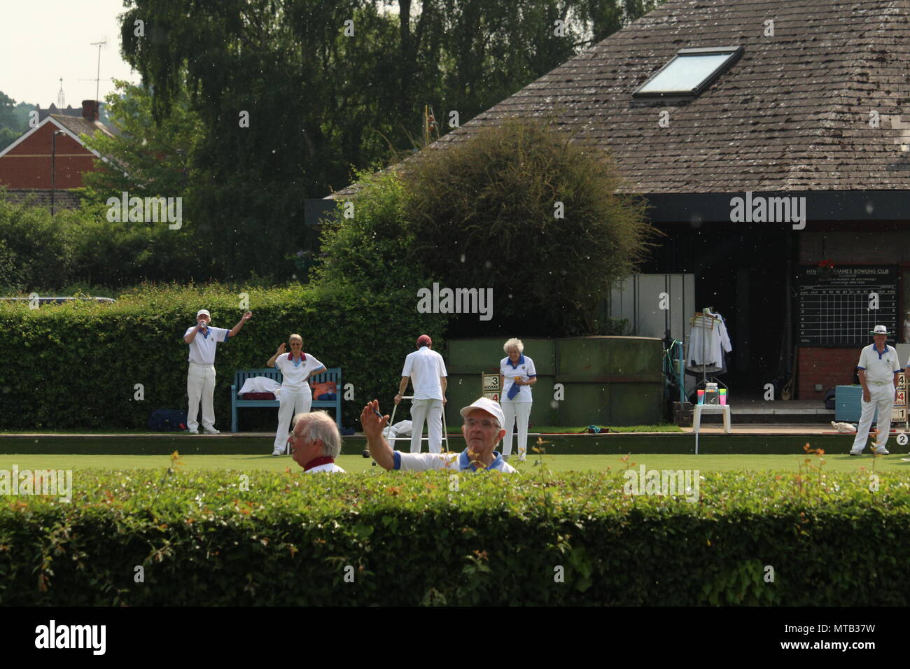 Sport and exercise - Bowlers happily waving from the pavillion lawn at Henley on Thames bowling club in Oxfordshire. Stock Photo
