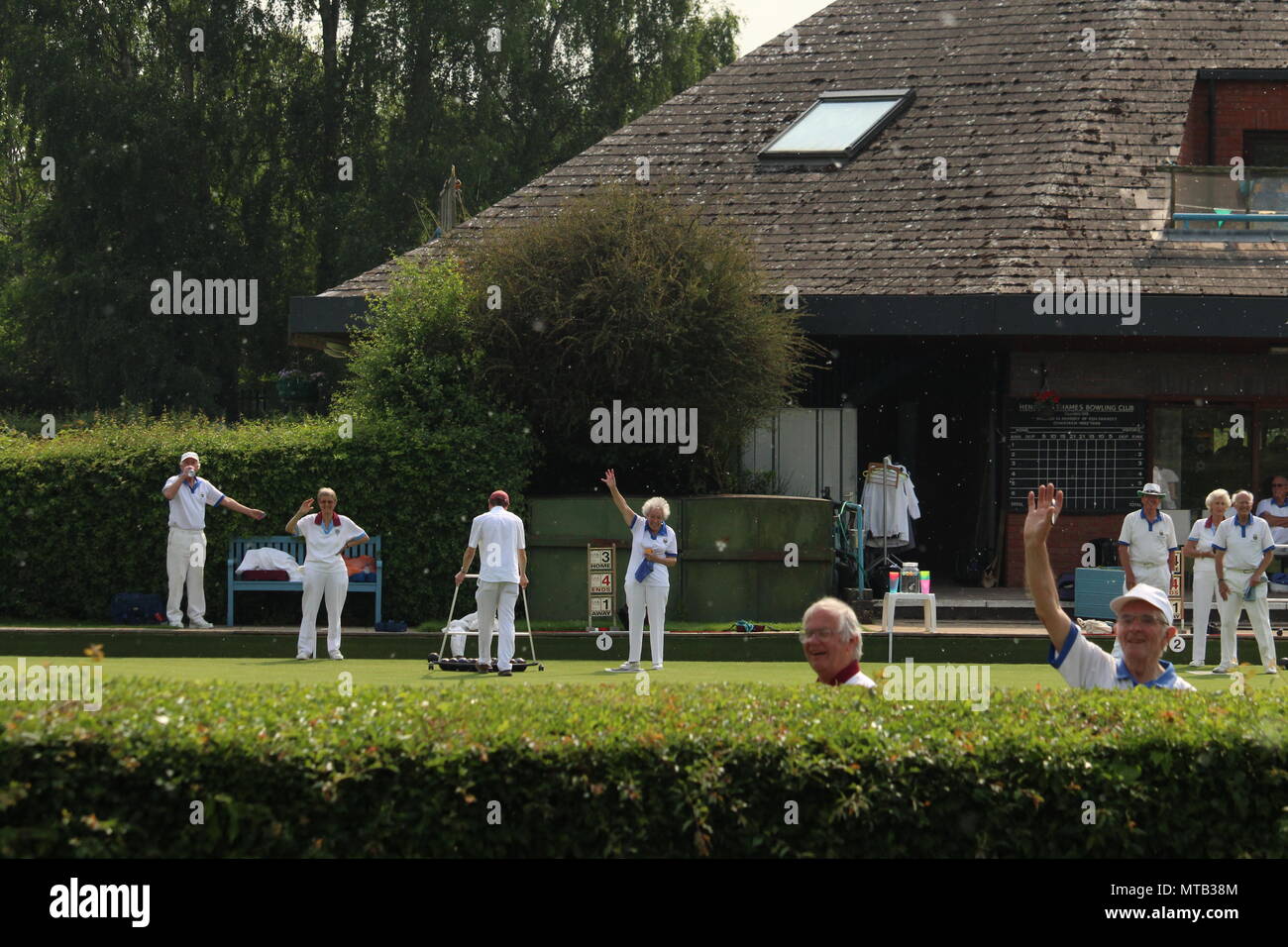 Sport and exercise - Bowlers happily waving from the pavillion lawn at Henley on Thames bowling club in Oxfordshire. Stock Photo