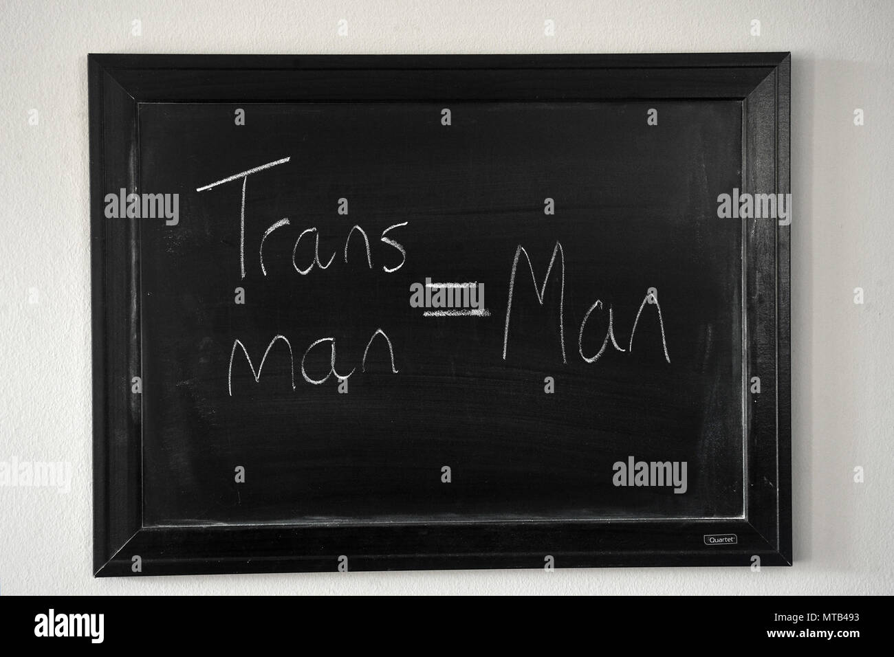Trans man = Man written in a white chalk on a wall mounted blackboard Stock Photo