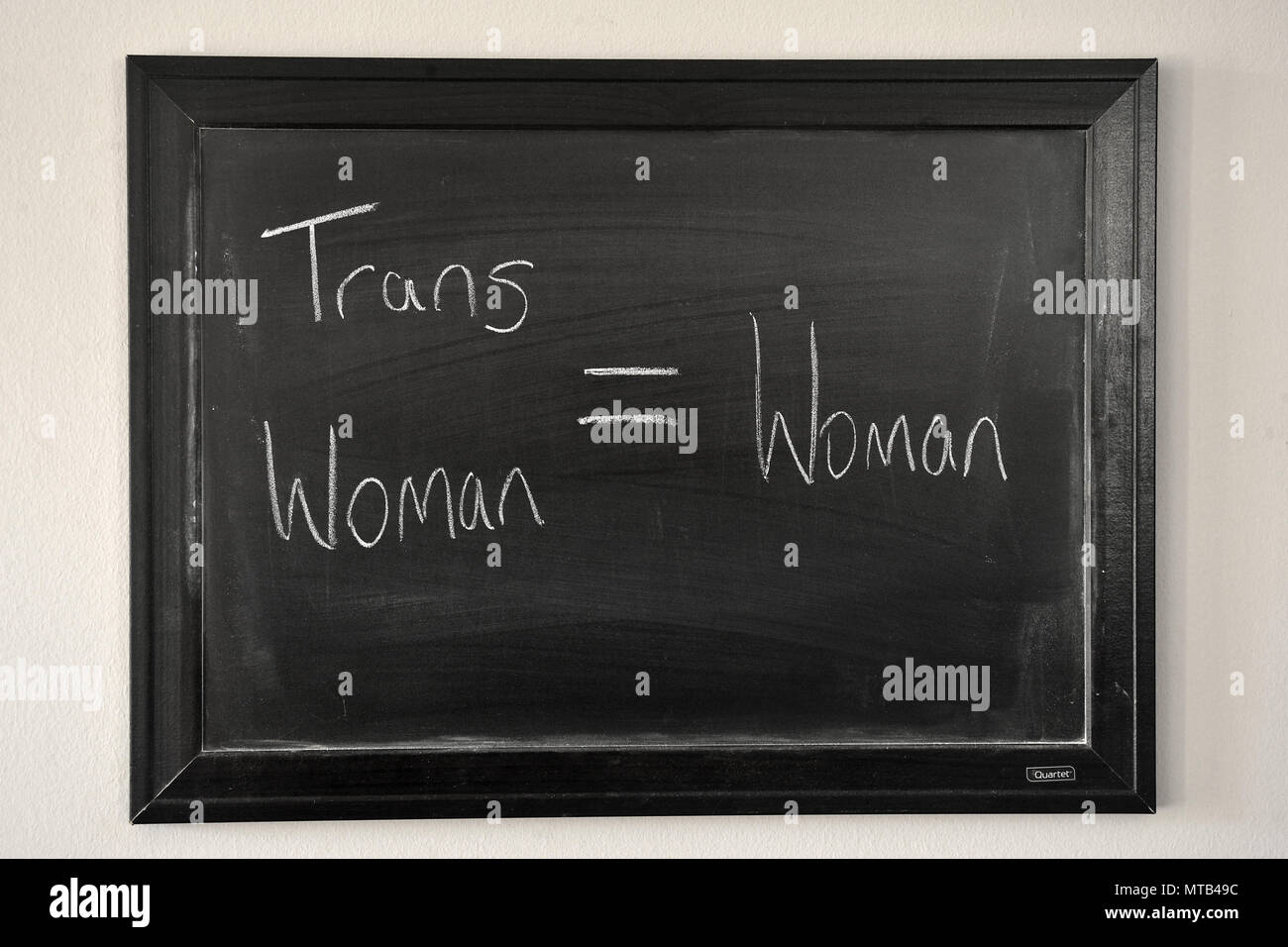 Trans woman = woman written in a white chalk on a wall mounted blackboard Stock Photo