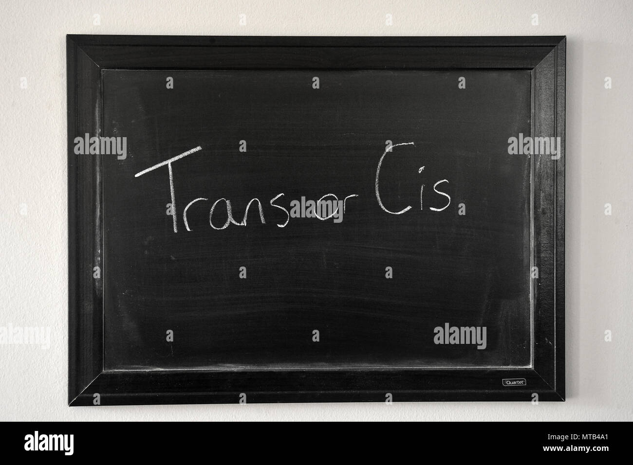 Trans or Cis written in a white chalk on a wall mounted blackboard Stock Photo