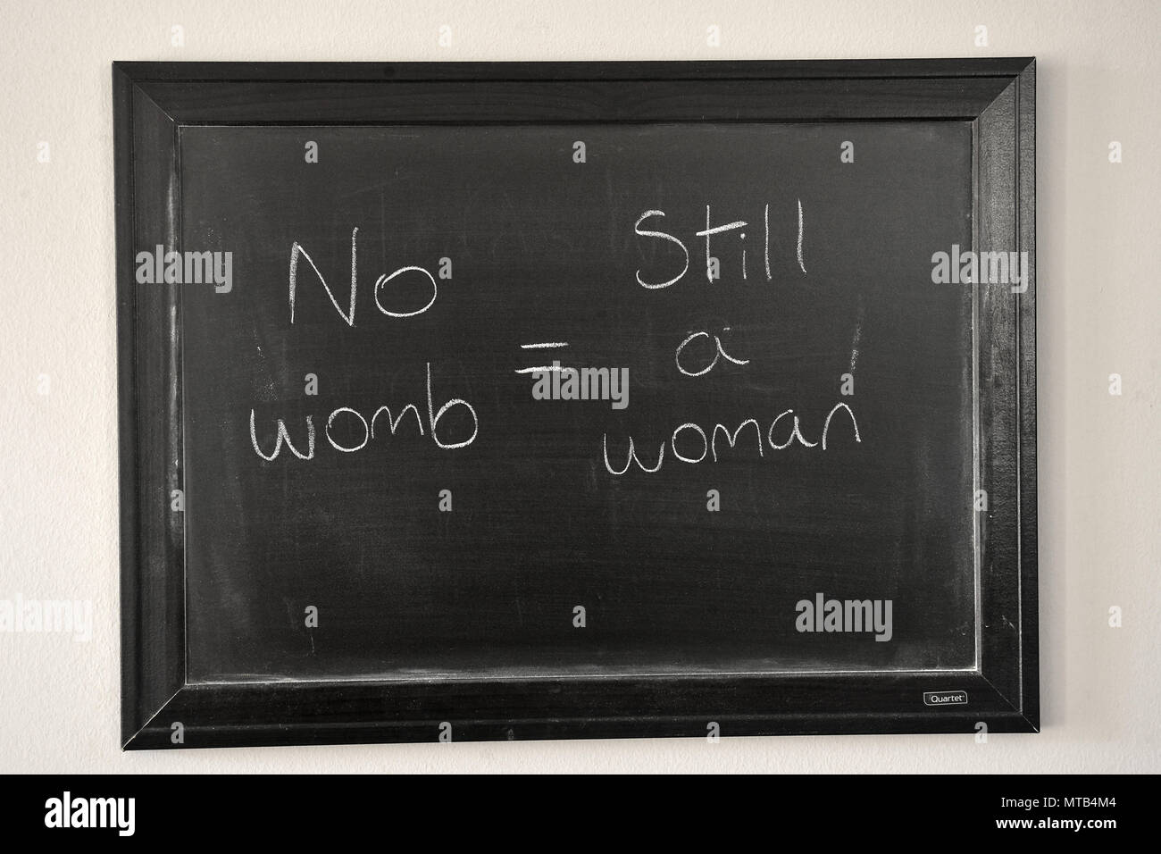 No womb = still a woman written in a white chalk on a wall mounted blackboard Stock Photo