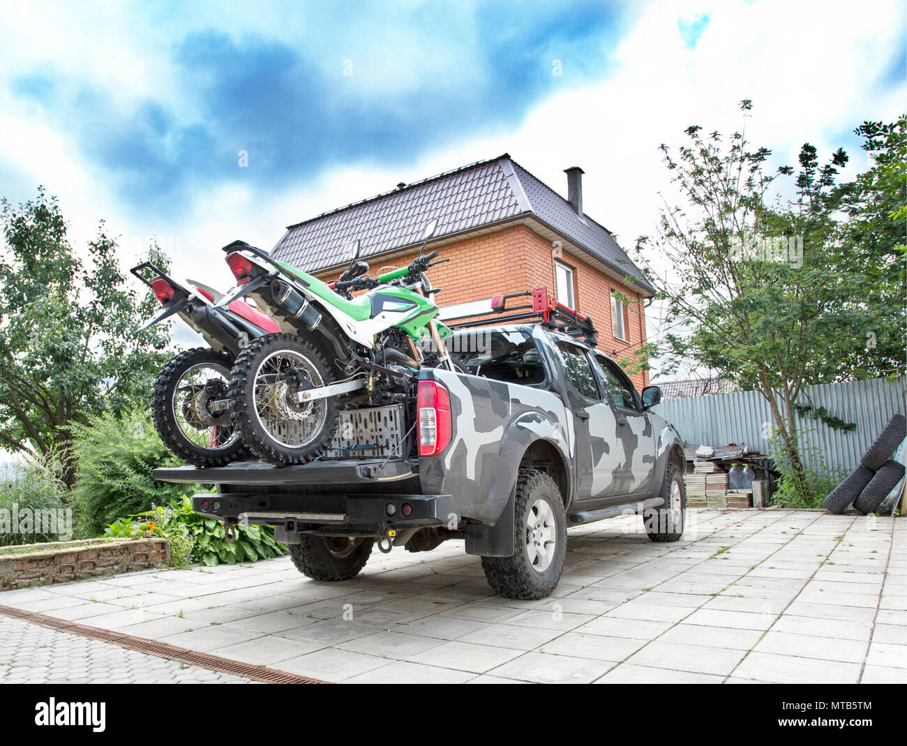 Two dirt bike motorcycles on the back of the camo truck on the d Stock