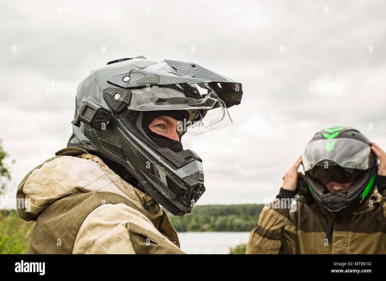 Two men outdoors wearing motorcycle helmets and uniforms Stock Photo