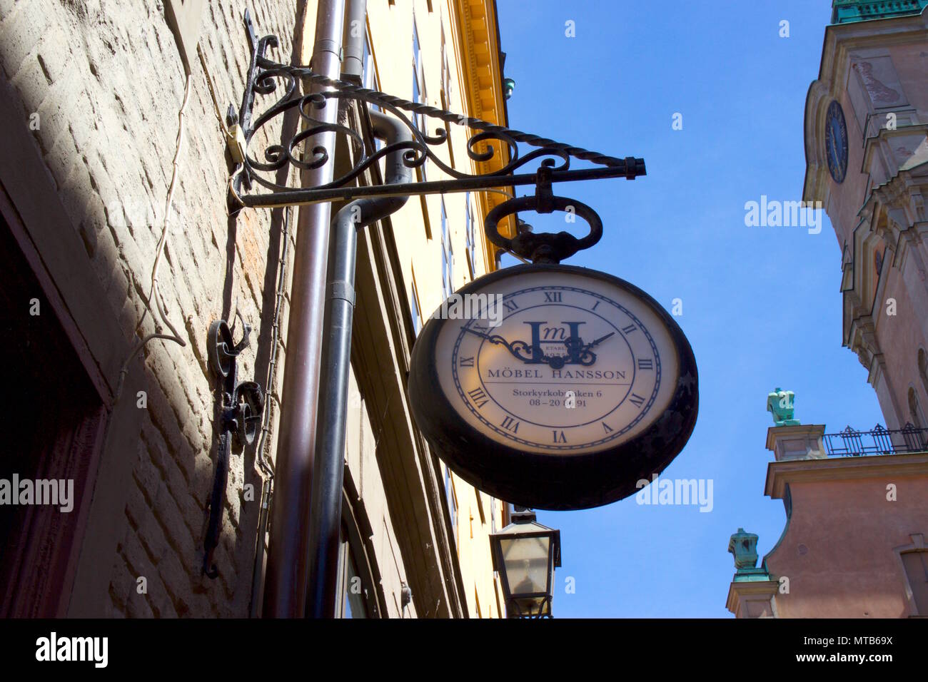A clock used as a shop sign for Mobel Hansson, which is an antique shop on Storkyrkobrinken, Gamla Stan, Stockholm, Sweden Stock Photo