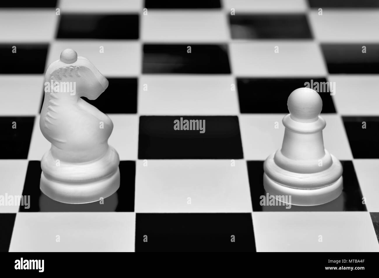 Chess game pieces. The knight and pawn against each other. Concept of opposition and confrontation. Stock Photo