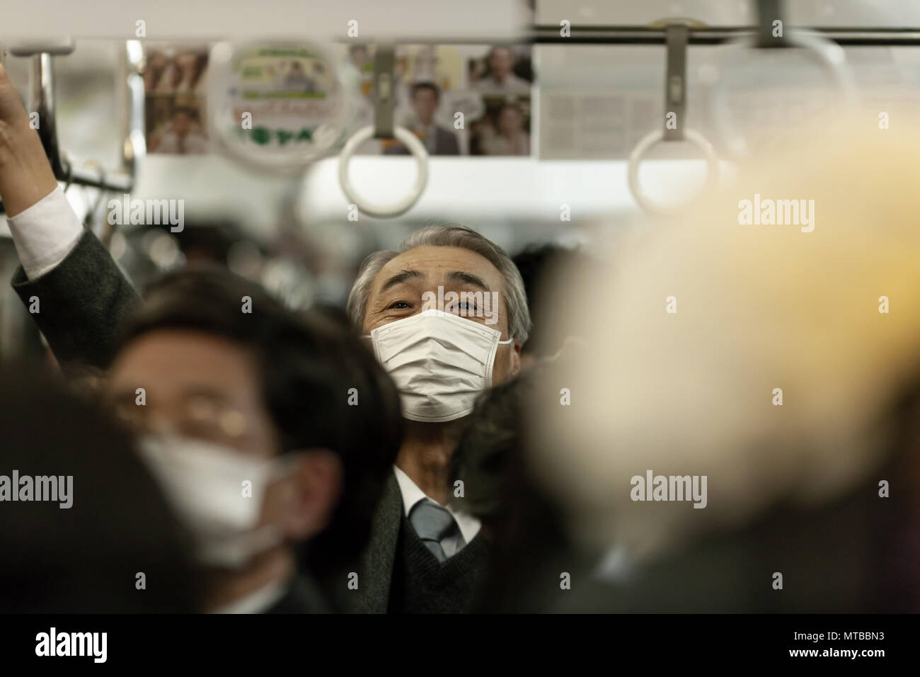 Grey-haired Japanese man with facemask in underground train in Tokyo, Japan Stock Photo