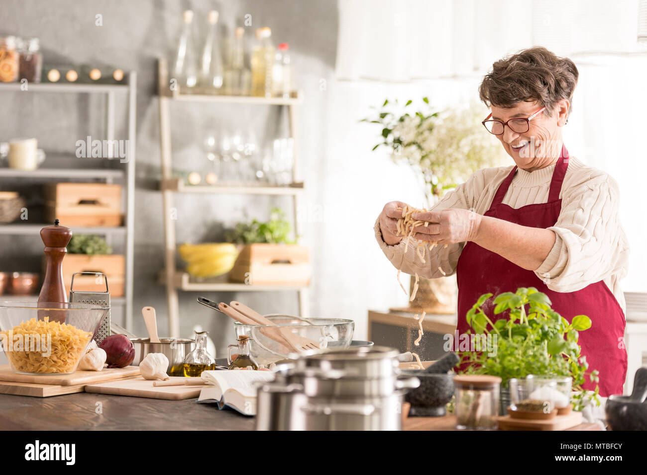 Happy senior woman cooking in her modern kitchen Stock Photo
