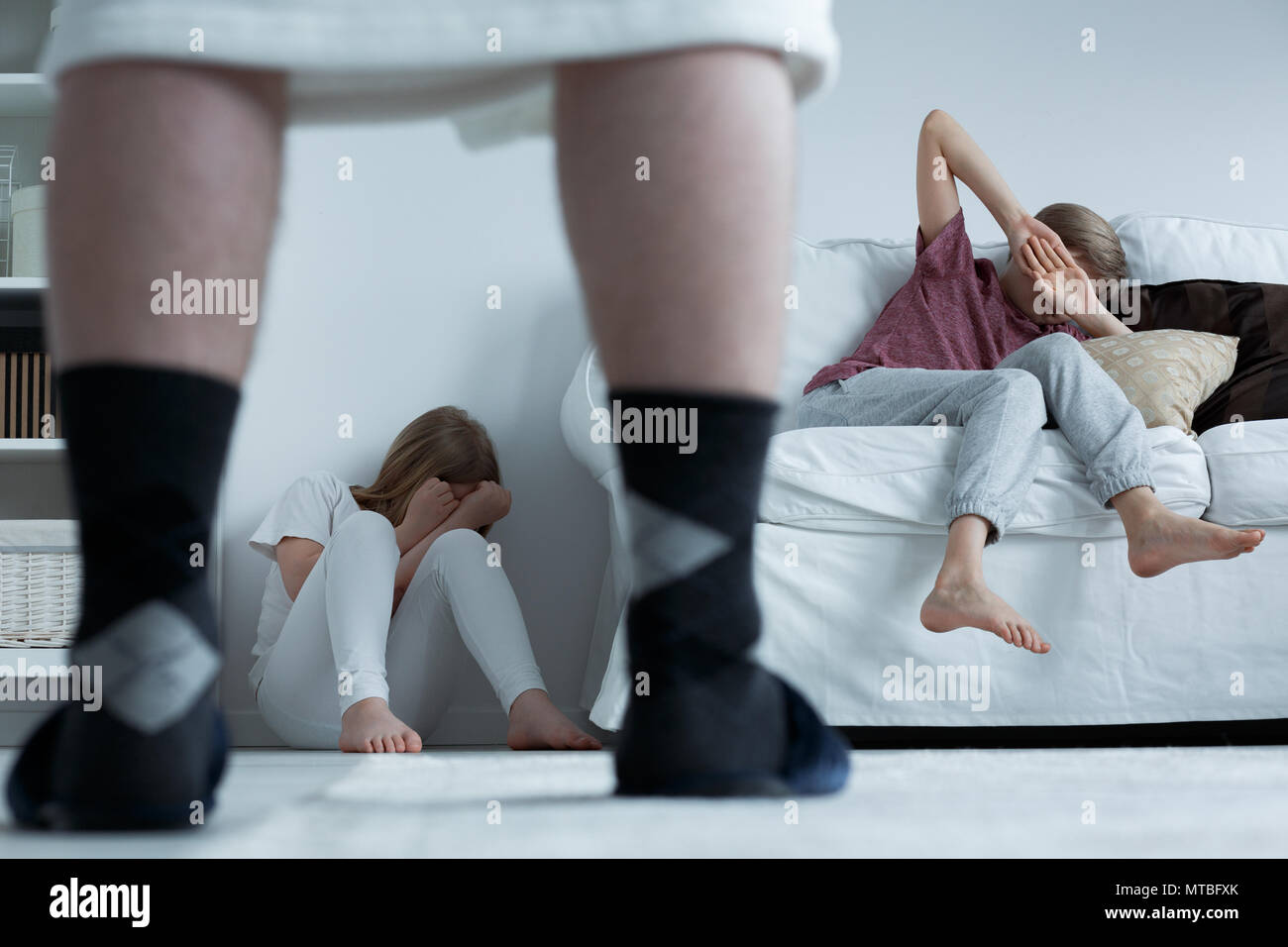 Terrified children hiding from their aggressive father Stock Photo