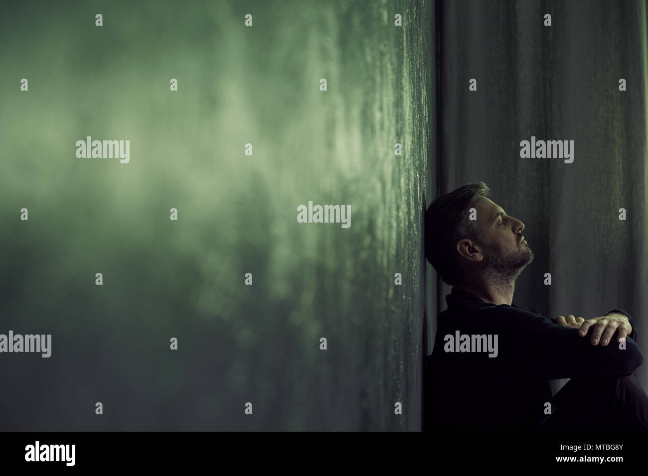 Depressed man sitting alone in gloomy room Stock Photo - Alamy