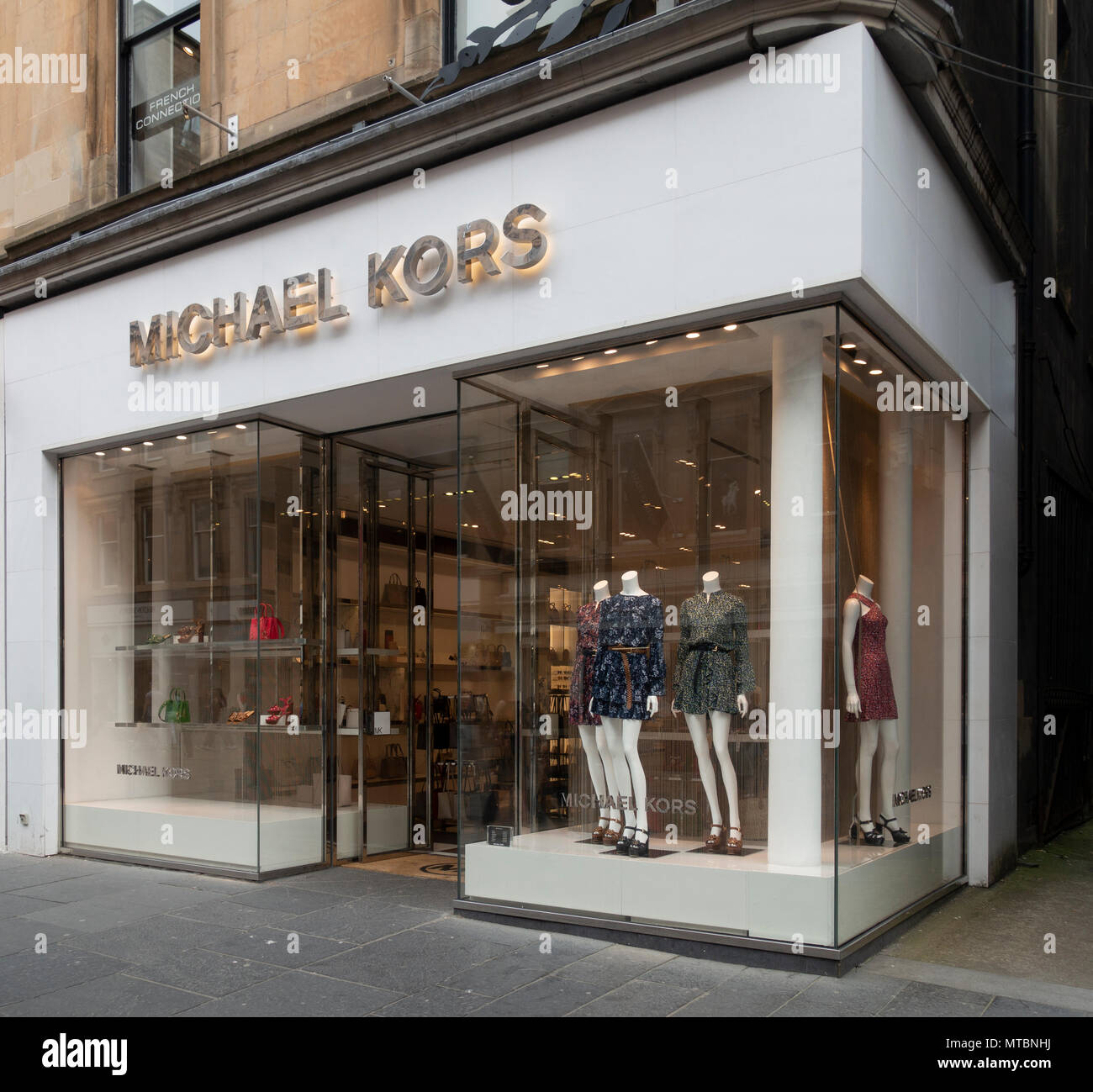 Womens' dresses, handbags and sandals on display in the Michael Kors shop in Buchanan Street, Glasgow. Window display and open entrance door. Scotland Stock Photo