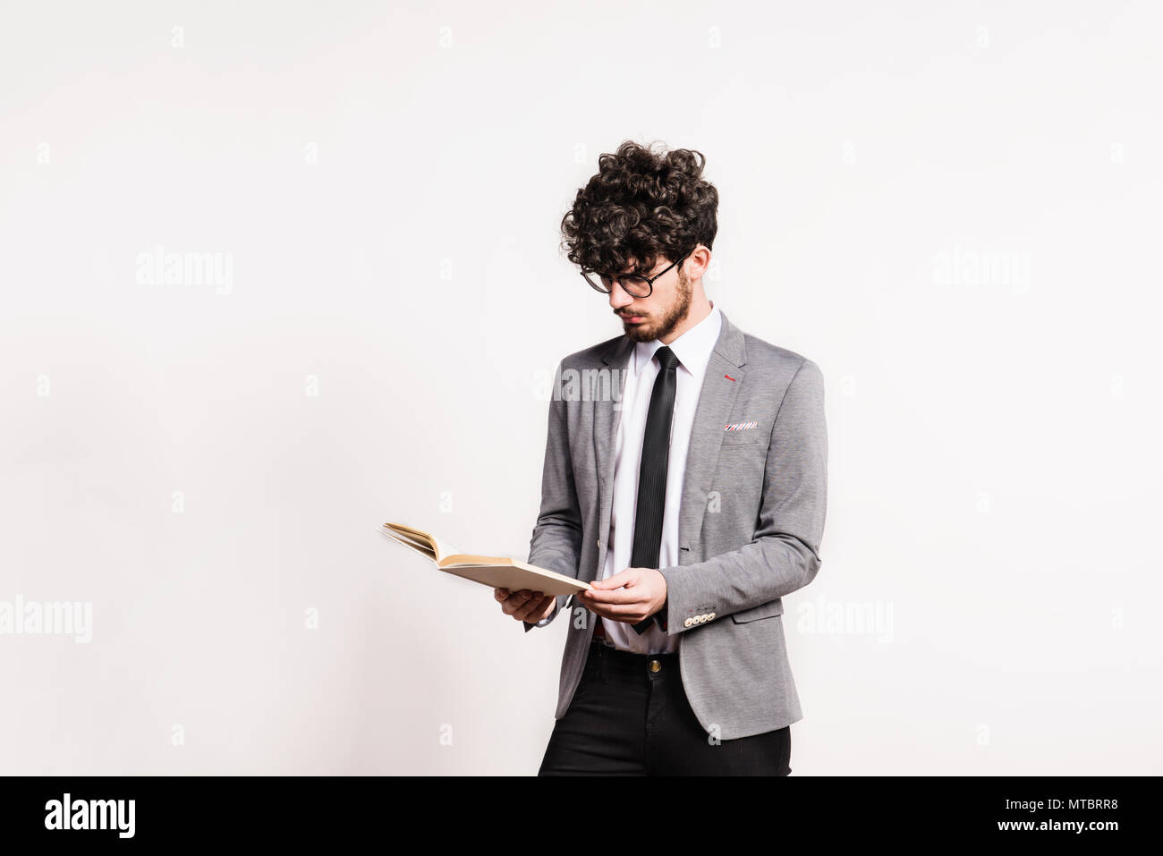 Portrait of a young man with a book in a studio on a white background ...