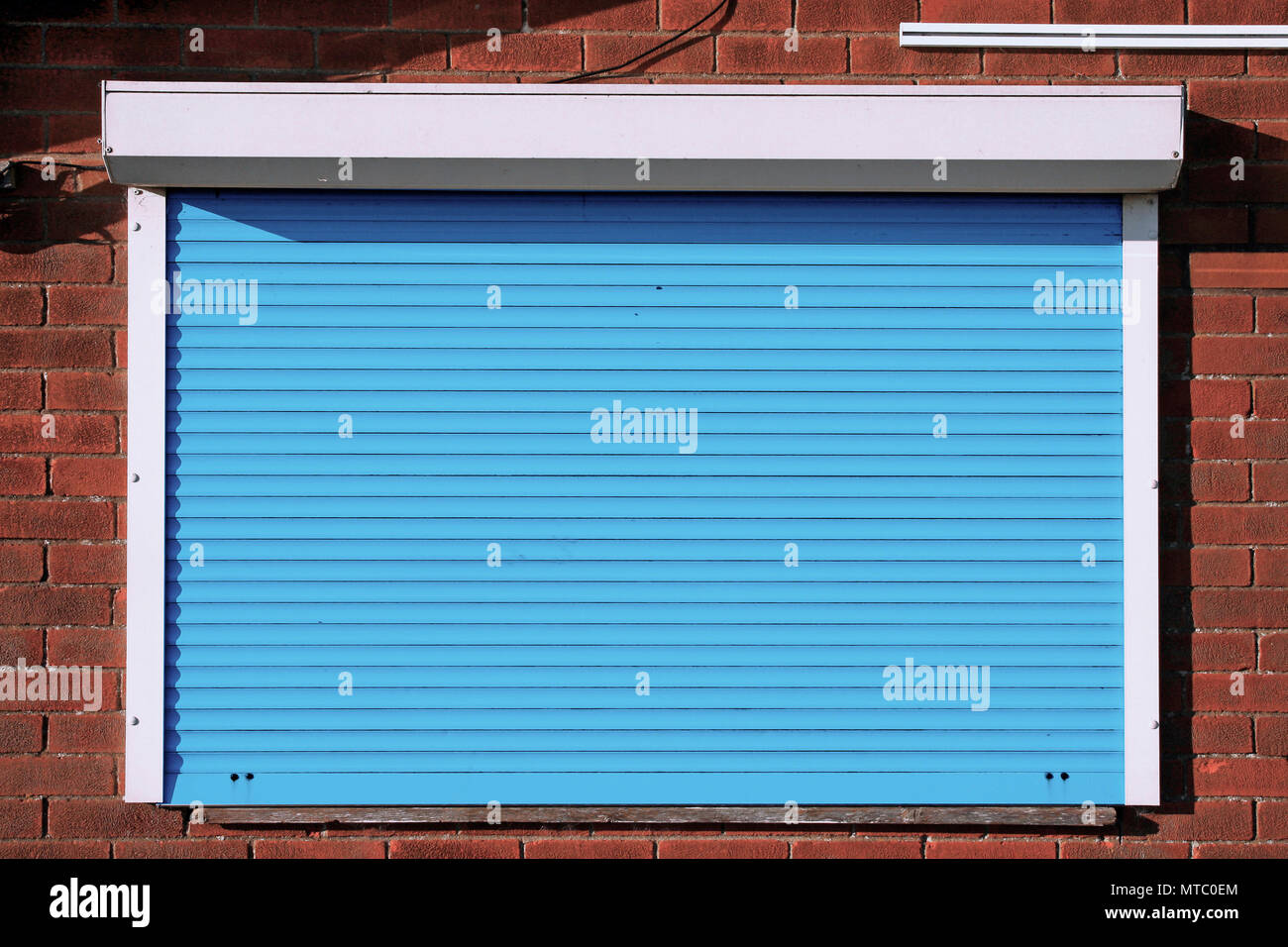 Closed blue serving hatch security shutters with brick background Stock  Photo - Alamy