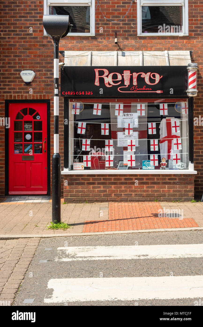 Retro styled barber's shop in Fordingbridge, Hampshire, UK,with window decorations of England flags ahead of the World Cup 2018 Stock Photo