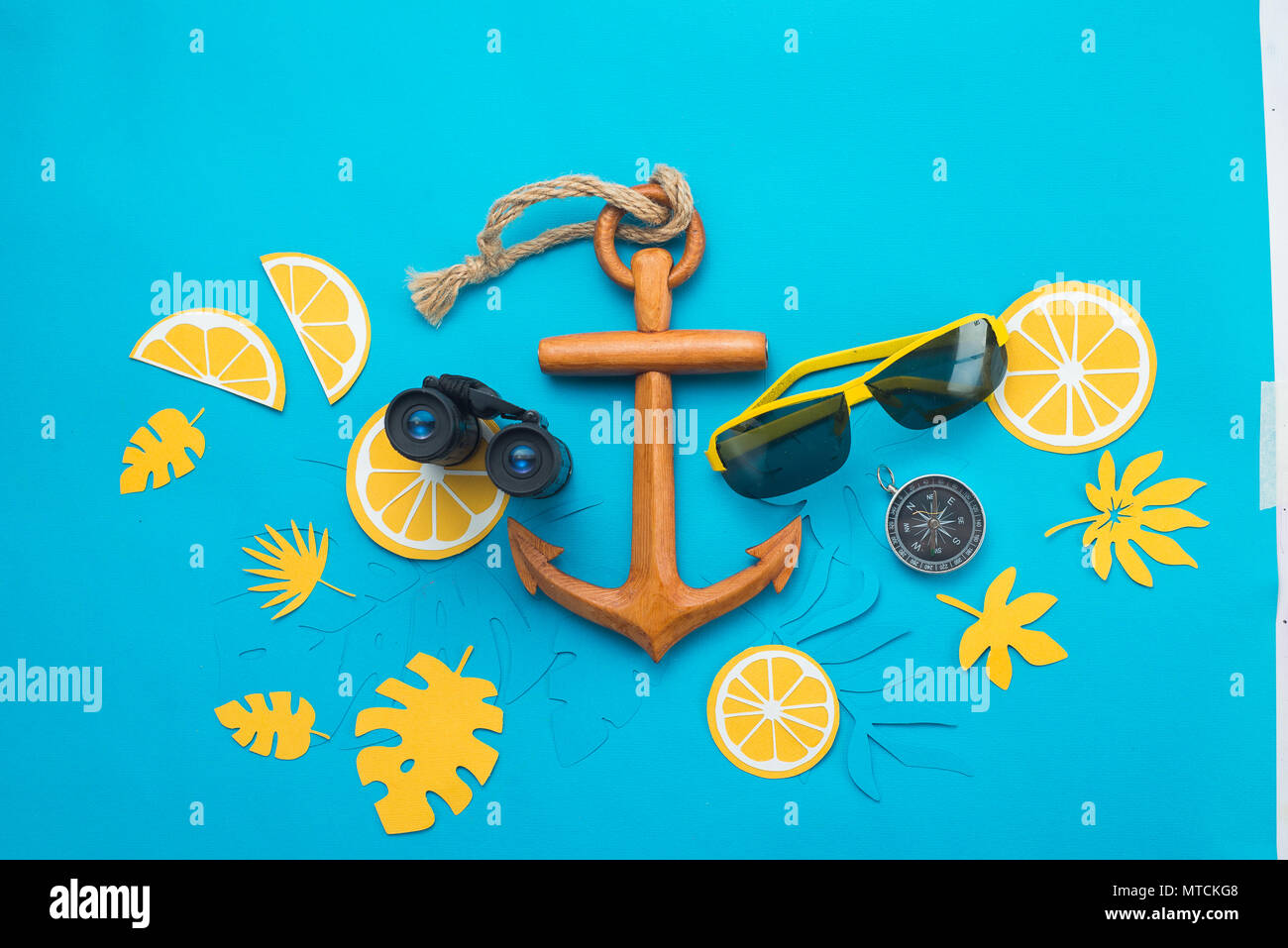 Sea travel background with sunglasses, binoculars, anchor, compass and tropical leaves on a bright blue background. Summer vacation concept with copy  Stock Photo
