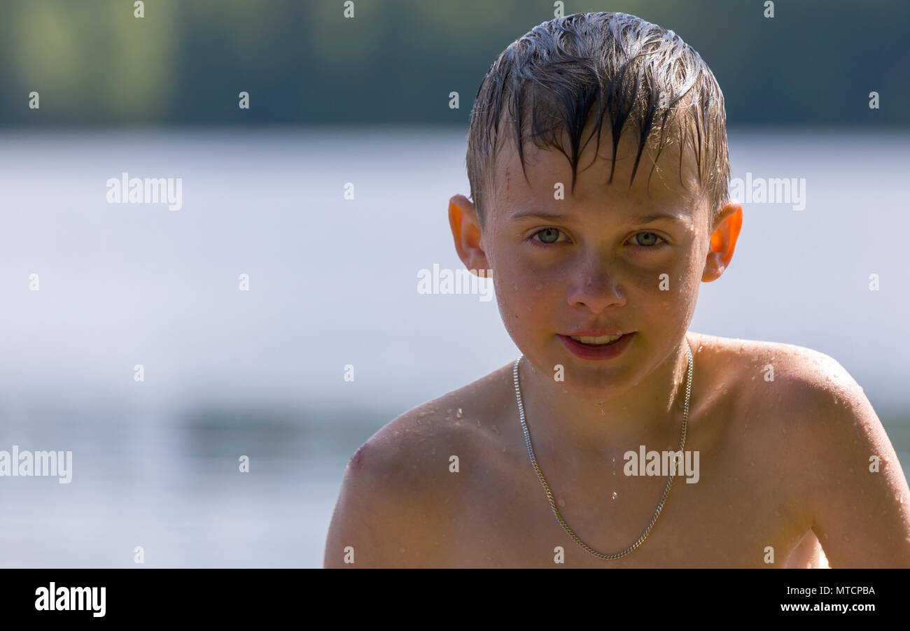 Young handsome dripping wet caucasian boy getting up and out of water