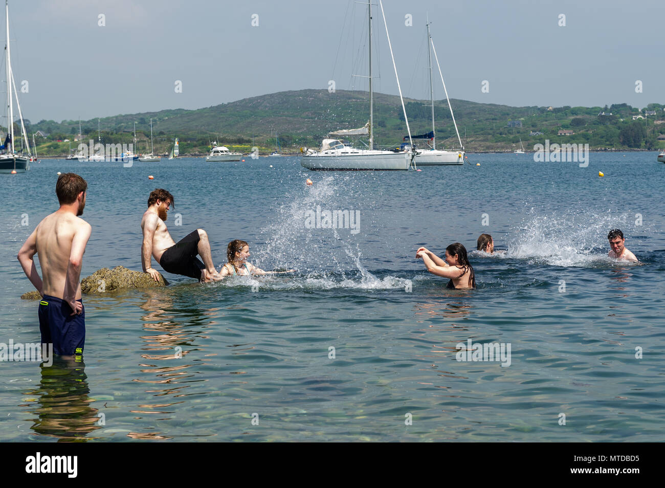 Schull, Ireland. 29th May, 2018.  On the hottest day of the year in West Cork,a group of friends cool off in Schull Harbour. Warm sunshine and highs of up to 27 C will give way to heavy showers and possible thunderstorms later in the day. Credit: Andy Gibson/Alamy Live News. Stock Photo